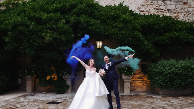 Recién casados en el Castillo de Tous, usando bengalas de humo de diferentes colores, disfrutando de una celebración animada y llena de color